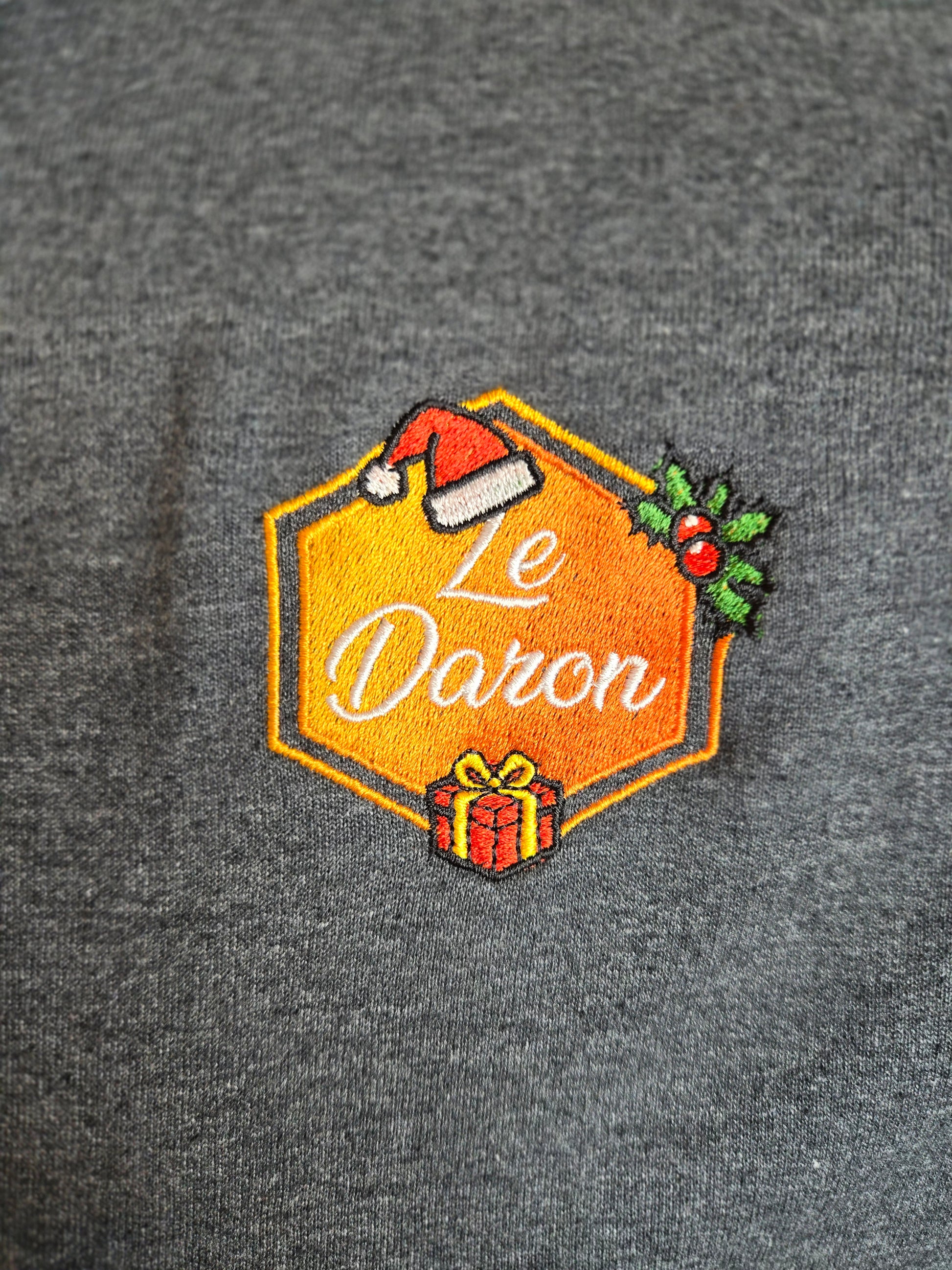 Gros plan sur la broderie édition Noël du Daron, logo orange avec bonnet et cadeau.