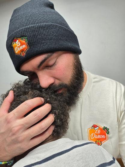 Bonnet et t-shirt du Daron édition Noël portés par un papa câlinant son enfant.
