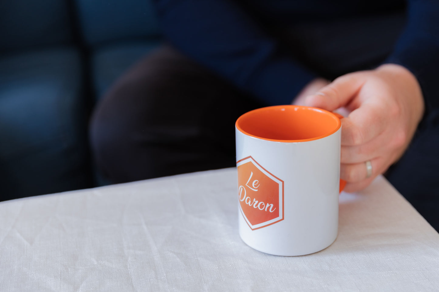 Mug Le Daron blanc - logo orange brodé - posé sur une table de salon